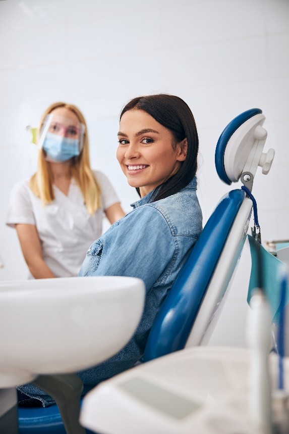Eine Zahnärztin und ihre Patientin lächeln freundlich in die Kamera.