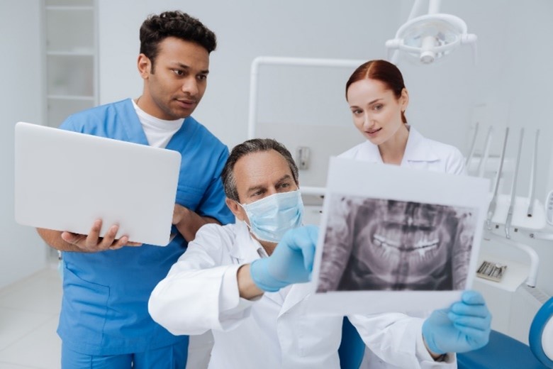 Ein Zahnarzt bespricht mit seinem Team die Röntgenbilder des Patienten