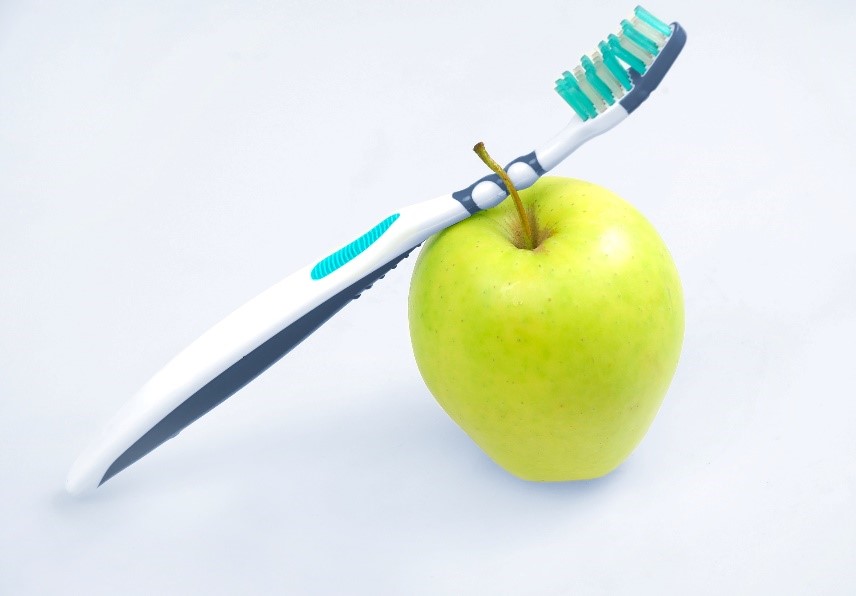 Leichte zahngesunde Ernährung Eine Zahnbürste ist an einem grünen Apfel angelehnt