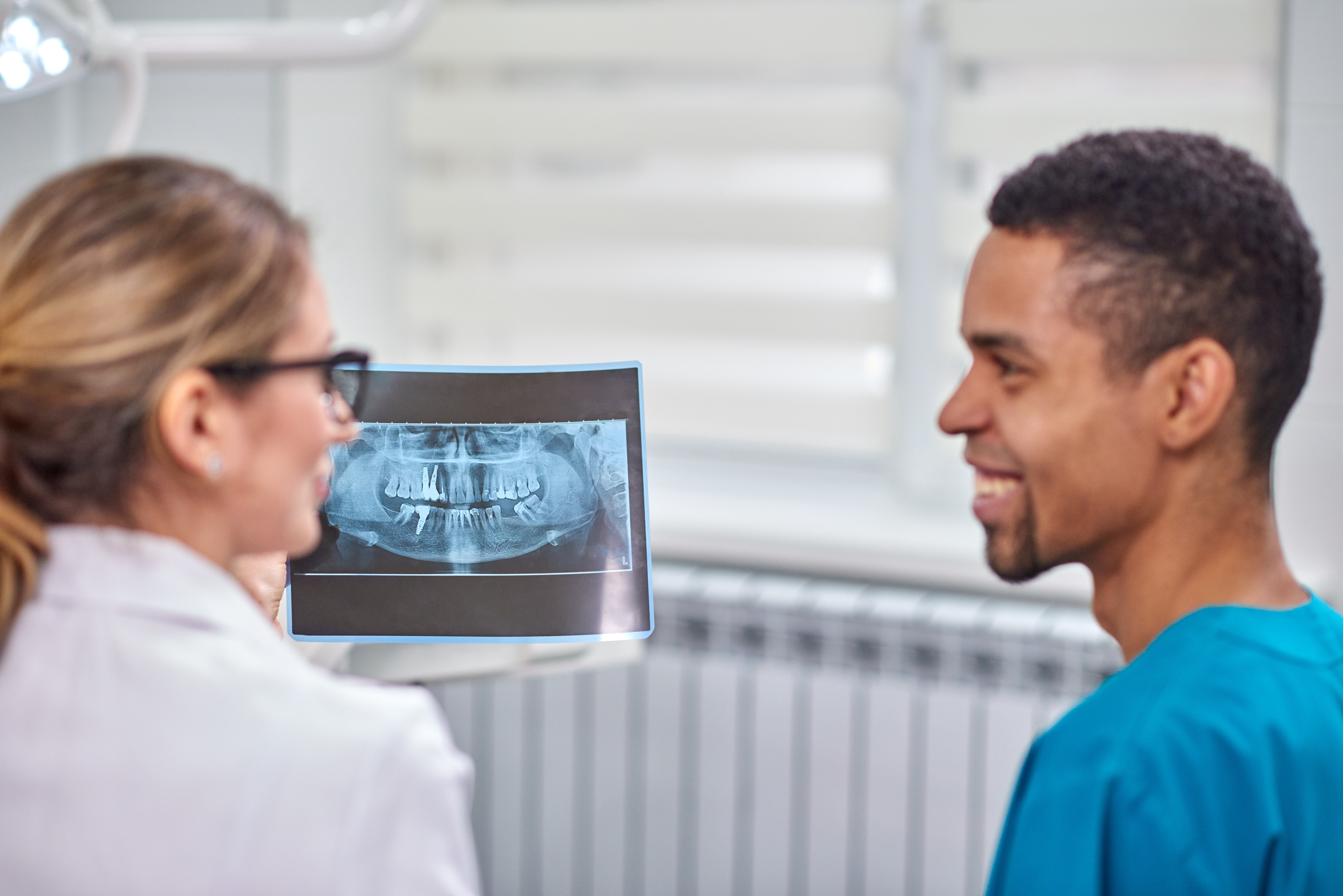 Eine Zahnärztin bespricht ein Röntgenbild mit ihrem Patienten.