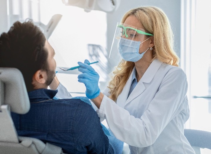 Eine Zahnärztin schaut sich die Zähne ihres Patienten an.